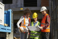 Workers looking at plan with hardhats on.