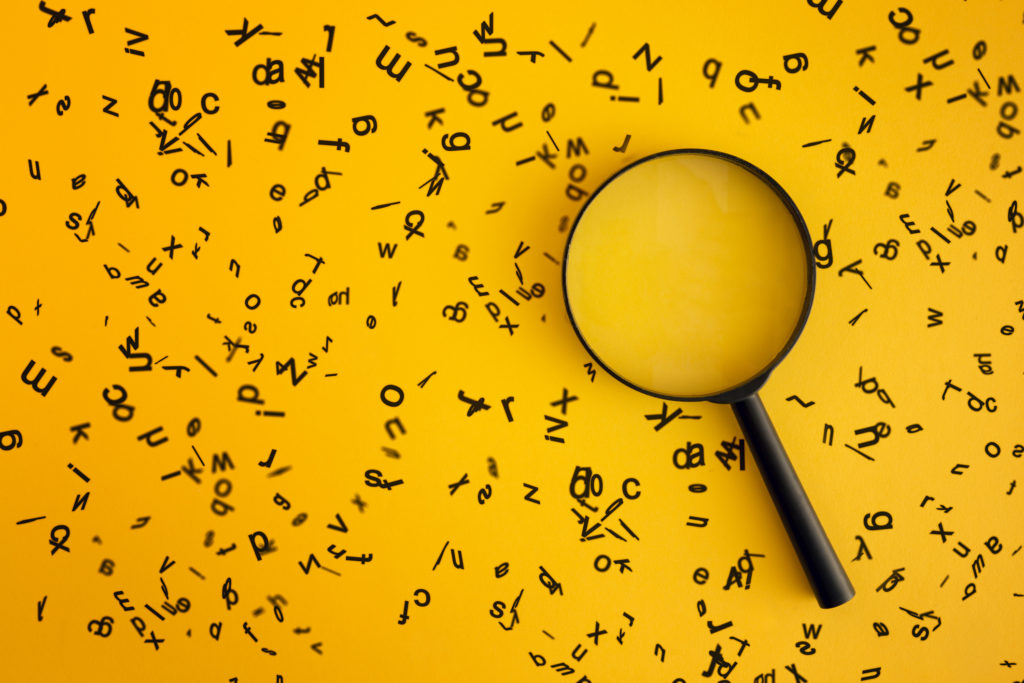 Magnifying on yellow background soundeded by black alphabets letters